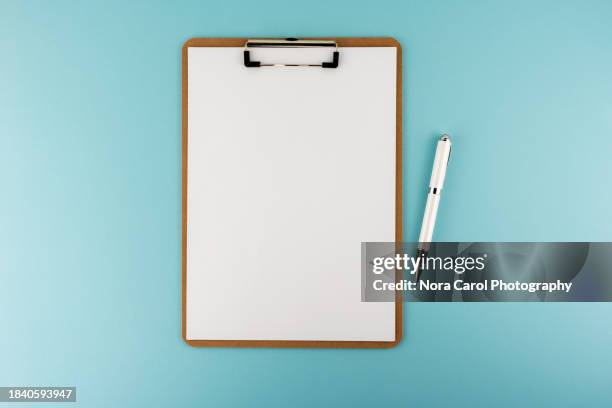 blank clipboard and pen on blue background - tablilla con sujetapapeles fotografías e imágenes de stock