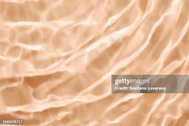 closeup of clear water surface texture with splashes and bubbles. trendy abstract nature background. ripple water texture on beige background. peach color. colour of the year 2024. trendy colours. - peach colour stock pictures, royalty-free photos & images