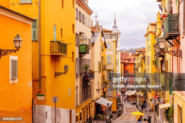 street with colourful buildings in nice old town, french riviera, france - historische wijk stockfoto's en -beelden