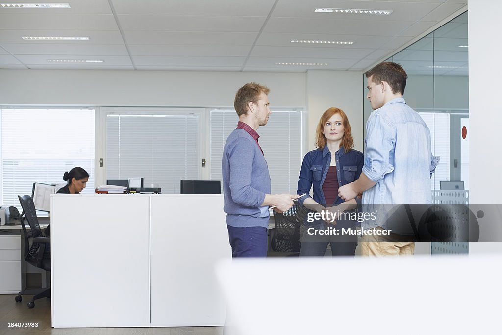 Three coworkers in discussion in office