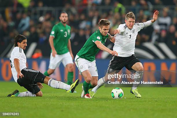 Bastian Schweinsteiger of Germany and his team mate Sami Khedira battle for the ball with Kevin Doyle of Ireland during the FIFA 2014 World Cup...