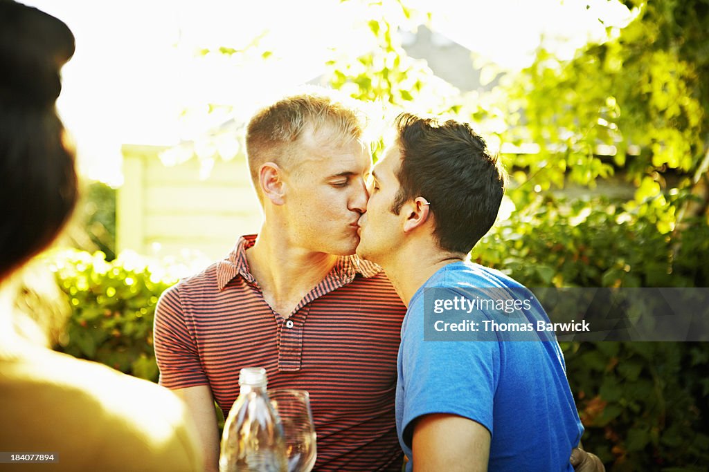 Kissing gay couple at backyard party with friends