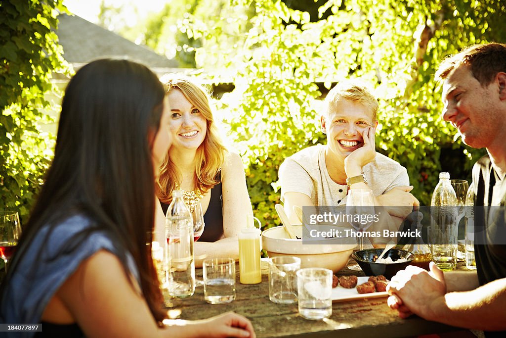 Smiling group of friends dining in backyard