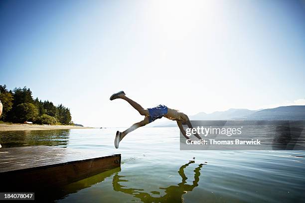 man diving off floating dock into water - schwimmende plattform stock-fotos und bilder