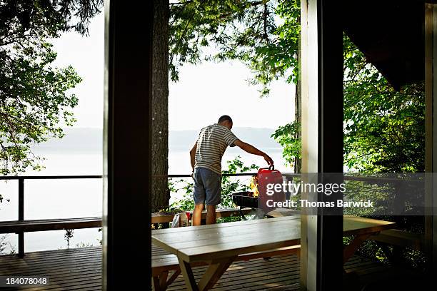 man preparing to cook on barbecue on deck of cabin - grillen balkon stock-fotos und bilder