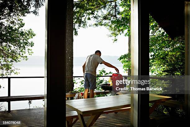 man preparing to cook on barbecue on deck of cabin - log cabin fire stock pictures, royalty-free photos & images