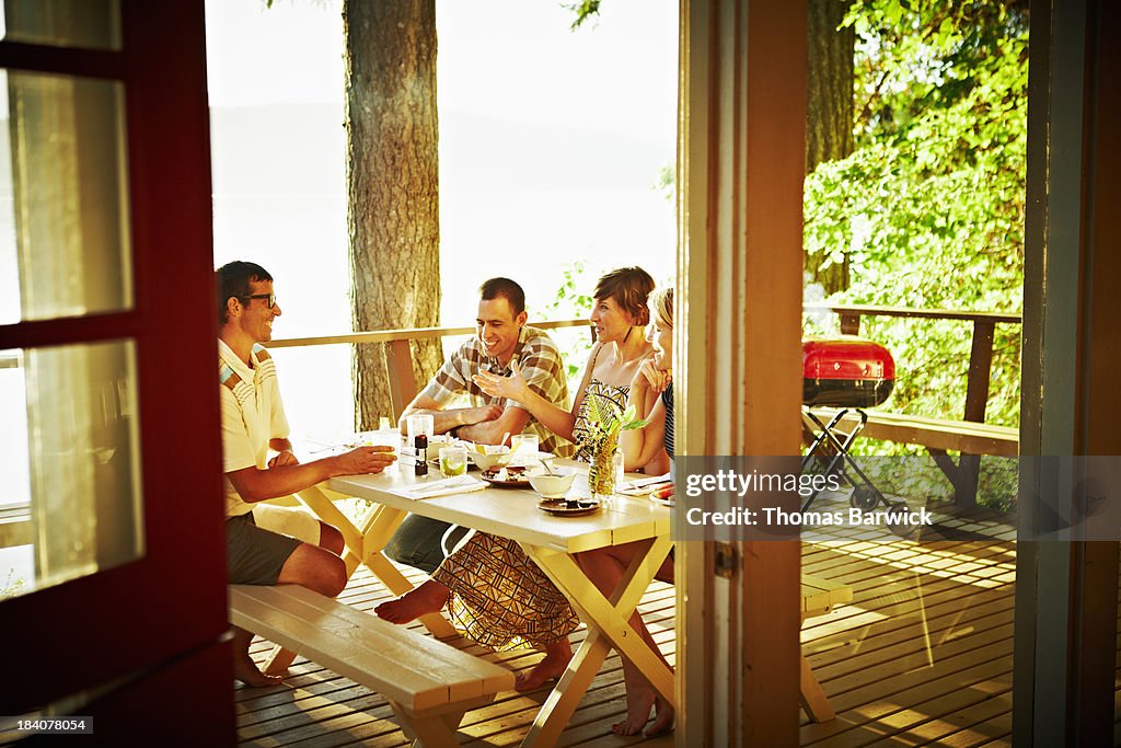 Group of friends dining on deck of cabin at sunset