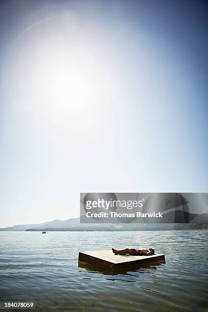 man lying on floating dock mountains in background - floating moored platform stock pictures, royalty-free photos & images