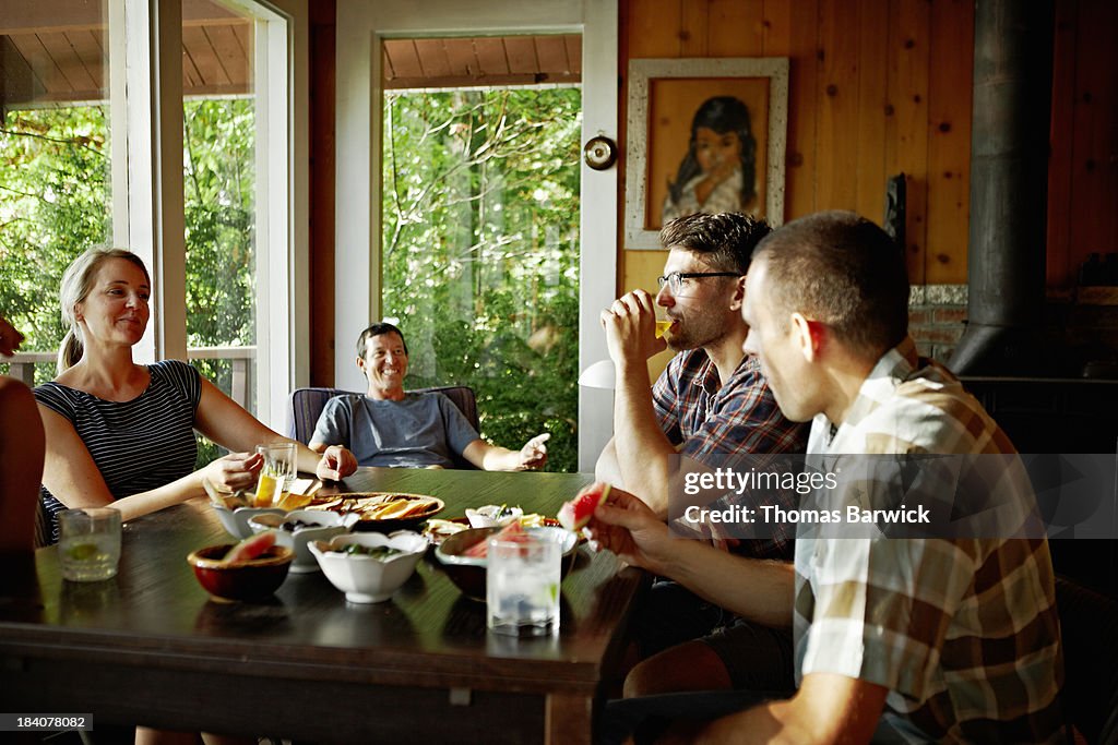 Friends talking and laughing at table in cabin
