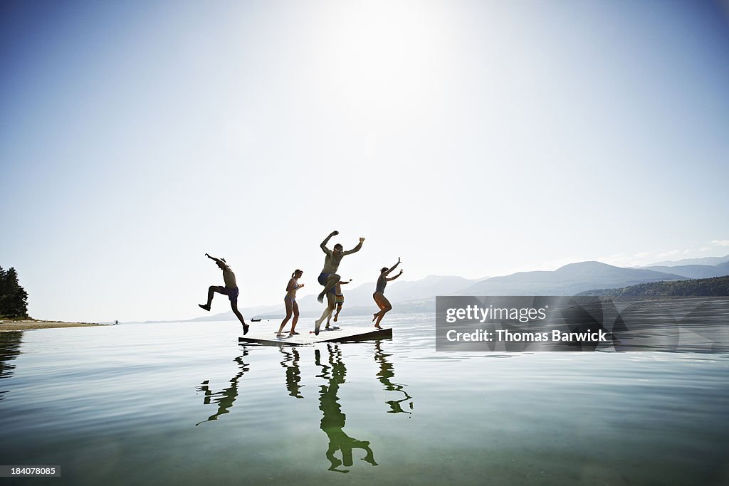 Group of friends jumping off floating dock