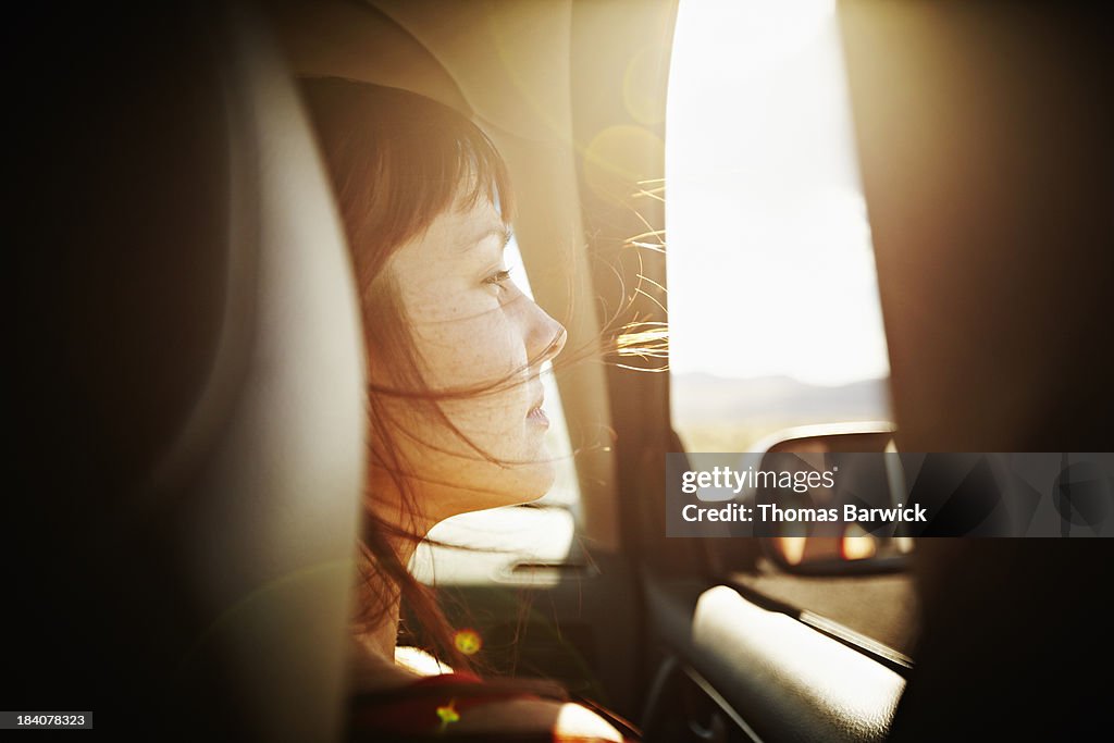 Woman with hair blowing looking out window of car