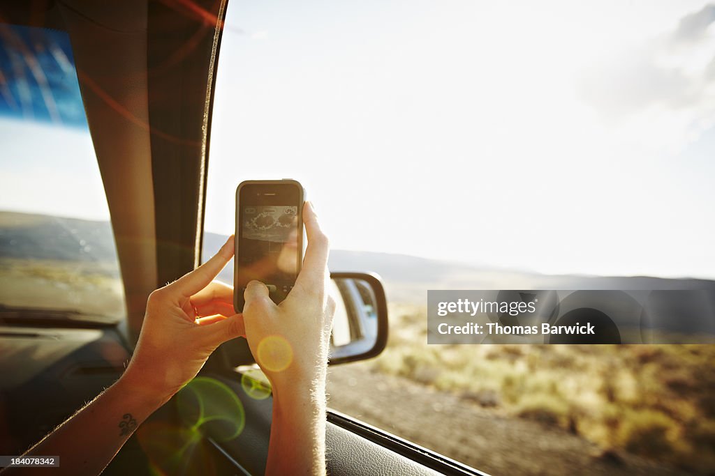 Woman riding in car taking photo with smartphone