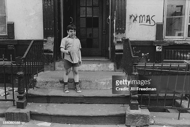 Boy brandishes his toy gun outside an apartment block in New York City, 1972.