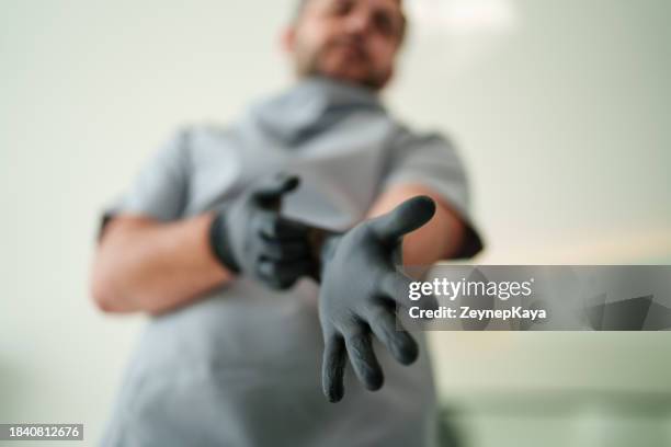 dentist wearing gloves, preparing for an examination. - luva preta imagens e fotografias de stock
