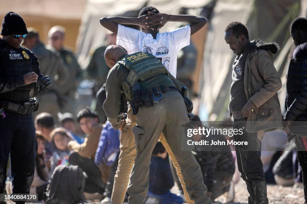 Border Patrol agent frisk an immigrant at a field processing center near the U.S.-Mexico border on December 08, 2023 in Lukeville, Arizona. A surge...