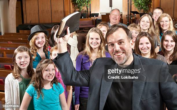 pastor holding bible with his people behind - gemeenteraad stockfoto's en -beelden