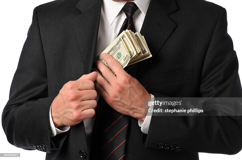 Businessman slipping stack of hundreds in his suit pocket