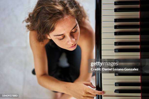 young woman sitting over floor while playing piano - composición fotografías e imágenes de stock