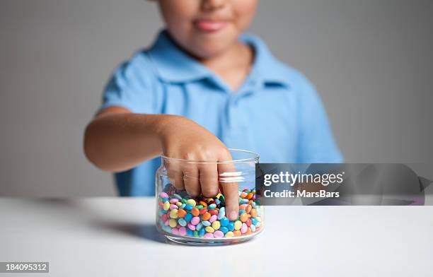 little boy taking candy from jar - candy jar stock pictures, royalty-free photos & images