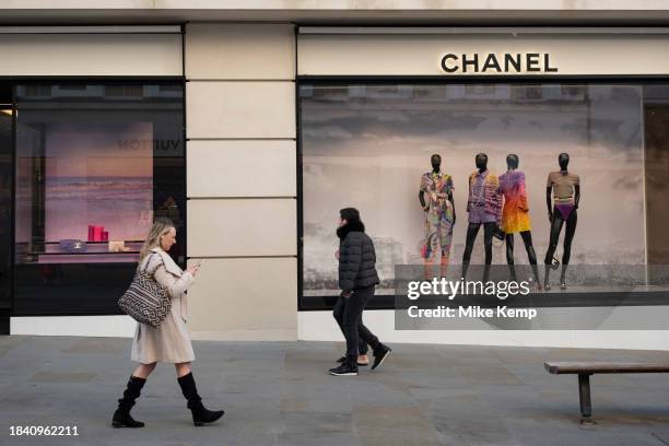 Figures of people interact with mannequins in the Chanel store window on Bond Street on 15th November 2023 in London, United Kingdom. Bond Street is...