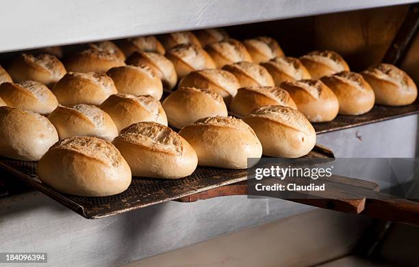 putting buns in oven - bakery stockfoto's en -beelden