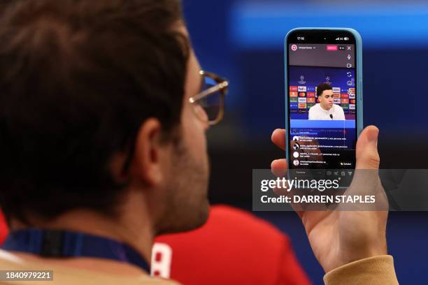 Journalist films as Bayern Munich's German midfielder Jamal Musiala attends a press conference at Old Trafford in Manchester, north-west England on...