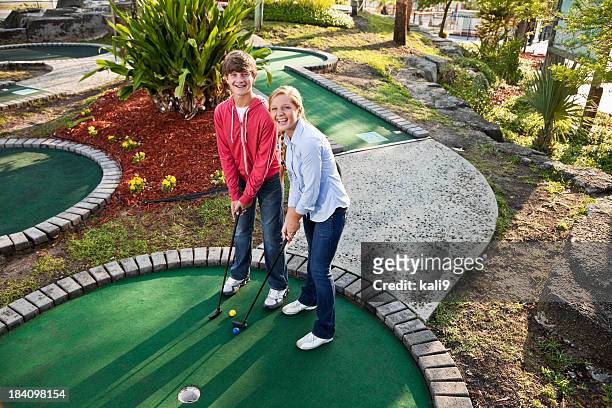 teenage couple playing miniature golf - miniature golf stock pictures, royalty-free photos & images