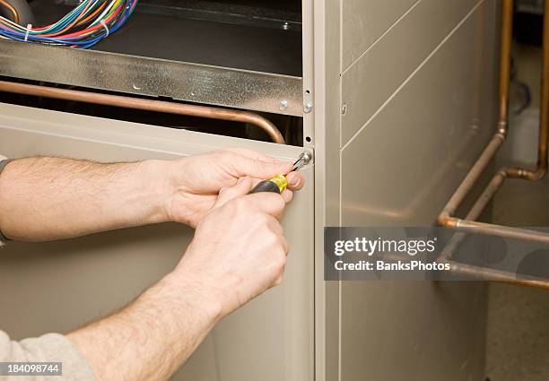 repair technician removing furnace service panel - home furnace stock pictures, royalty-free photos & images