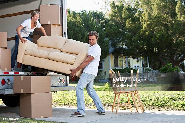 young couple moving house - couple on sofa stockfoto's en -beelden