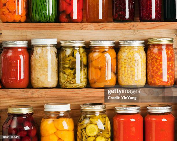 home canning fruit and vegetable food preserves in storage shelves - jar stockfoto's en -beelden