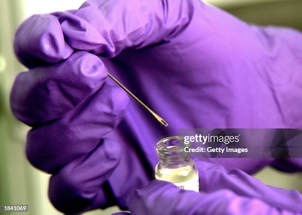 Navy medical technician holds a bifurcated vaccinating needled above a vial containing the vaccine for small pox March 5, 2003 at sea aboard the USS...