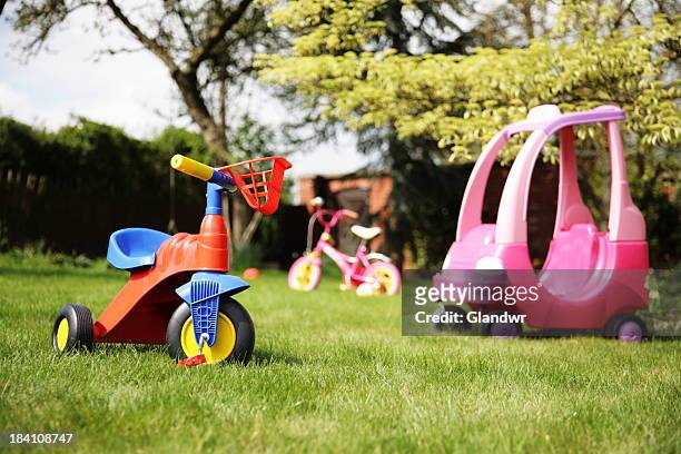 a yard with three children's toys in it - tricycle stock pictures, royalty-free photos & images