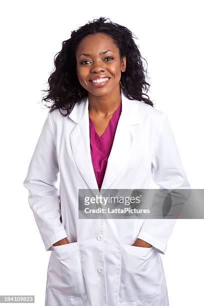 smiling african ethnicity female wearing lapcoat hands in pockets - doctor lab coat stock pictures, royalty-free photos & images