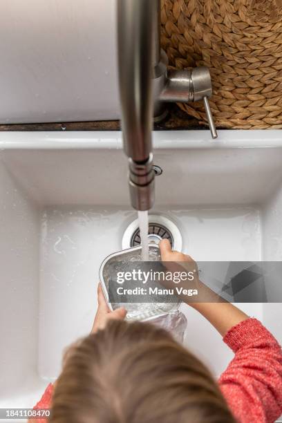 anonymous little girl washing dog food container - luva para lavar louça imagens e fotografias de stock