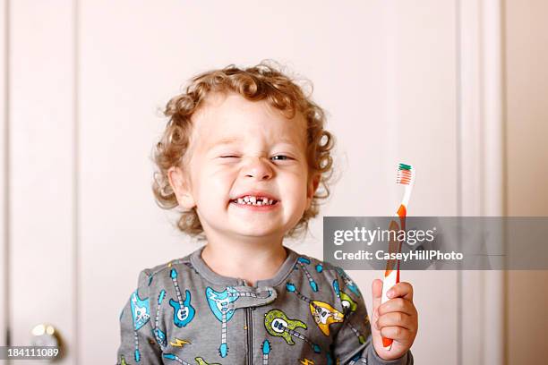 toddler smiling while holding a toothbrush - menselijk gebit stockfoto's en -beelden