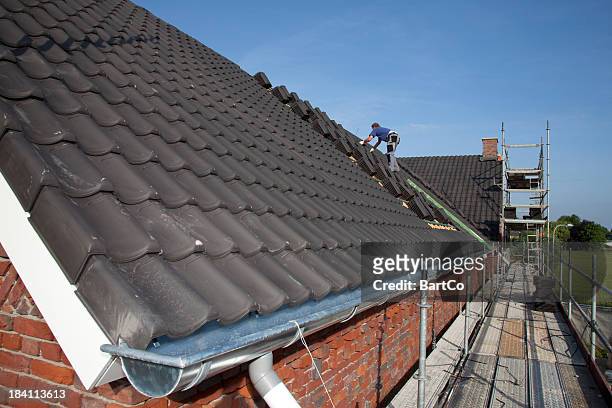 uomo che lavora sul tetto. - costruttore di tetti foto e immagini stock