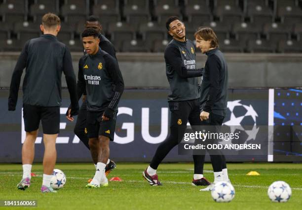 Real Madrid's English midfielder Jude Bellingham and Real Madrid's Croatian midfielder Luka Modric joke as they attend a training session in Berlin...