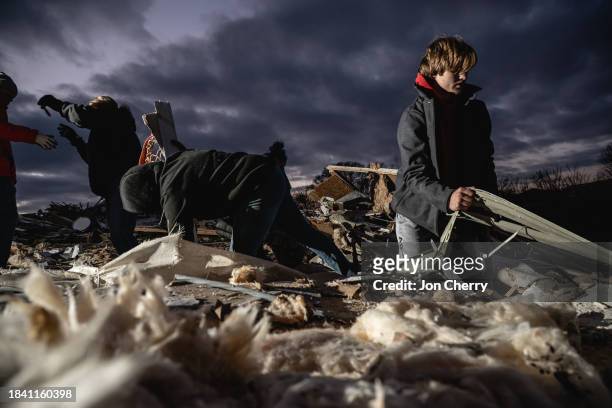 Residents and visitors work to clear debris in search of pets and belongings of a destroyed home in the aftermath of a tornado on December 10, 2023...