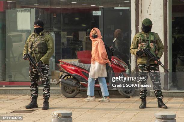 Kashmiri girl looks on as Indian paramilitary personnel stand guard along a road in Srinagar ahead of Supreme Court's verdict on Article 370. India's...