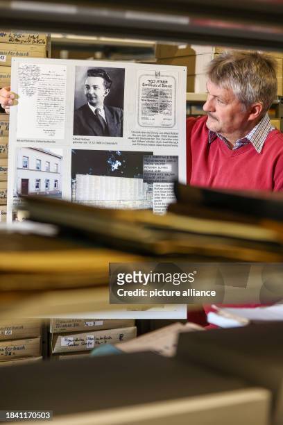 November 2023, Saxony, Falkenstein: Ralph Ide stands with an exhibition poster about Alfred Roßner in the Falkenstein town archive. Born in the small...