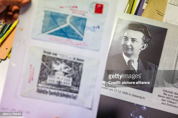 November 2023, Saxony, Falkenstein: Ralph Ide holds a copy of an envelope from the time of the Second World War in front of an exhibition poster on...
