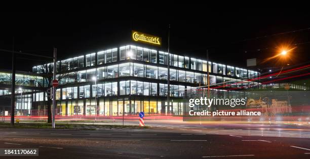 December 2023, Lower Saxony, Hanover: Lights shine in the new corporate headquarters of Continental AG, while passing cars leave trails of light....