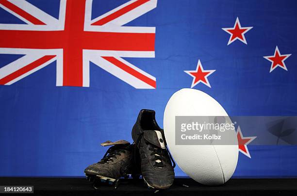 rugby ball and shoes in front of new zealand flag backdrop - new zealand rugby stock pictures, royalty-free photos & images