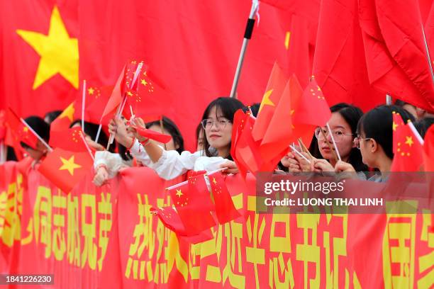 People wave Chinese and Vietnamese national flags ahead of the arrival of China's President Xi Jinping and his wife Peng Liyuan at Noi Bai...
