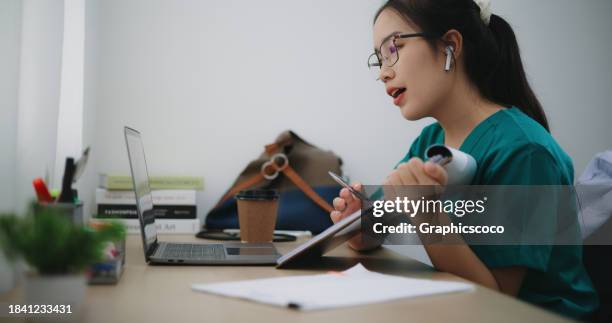 asian female doctor in a scrubs uniform using a computer laptop to take a video conference call - anatomy video bildbanksfoton och bilder