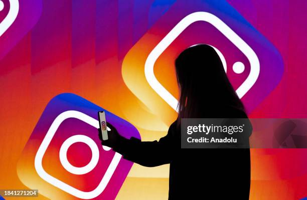 In this photo illustration, logo of 'Instagram' is displayed on mobile phone screen in front of a screen also displaying the 'Instagram' logo in...