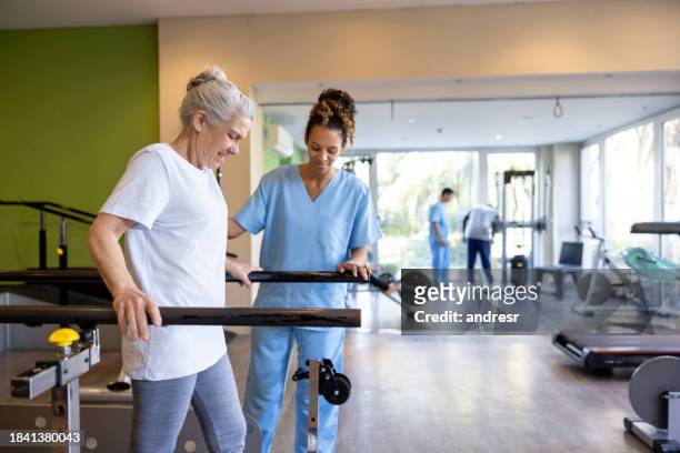 senior woman in physical therapy walking on the bars - rehabilitation center stock pictures, royalty-free photos & images