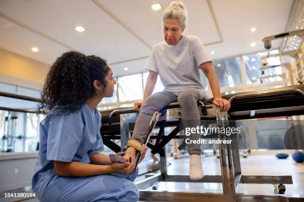physical therapist helping a senior woman with her ankle injury - rehabilitation center stock pictures, royalty-free photos & images
