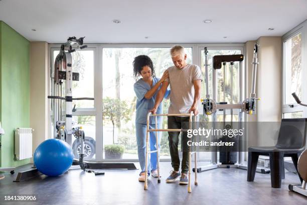 man in physical therapy trying to walk using a walker - gåstol ortopedisk utrustning bildbanksfoton och bilder