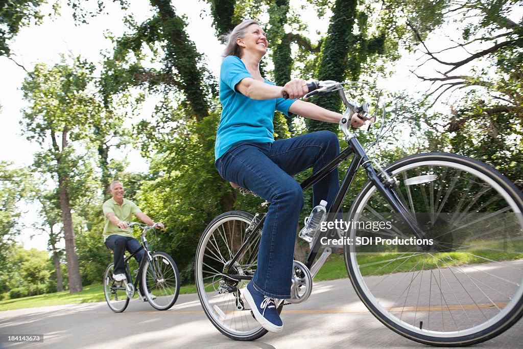 Ältere Erwachsene Frau Fahrradfahren auf dem Trail mit ihrem Ehemann vor